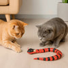 Jouet pour Chat - Serpent Interactif deux chats un roux un gris devant un canapé et un pot de fleur jouent avec le serpent sur le sol beige