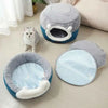 Panier Chat Coussin & Grotte – le Refuge Douillet pour Votre Félin ! 1 chat blanc gris regardant vers le haut, assis devant un rideau blanc et entre le lit et la grotte, au pied d'un canapé beige