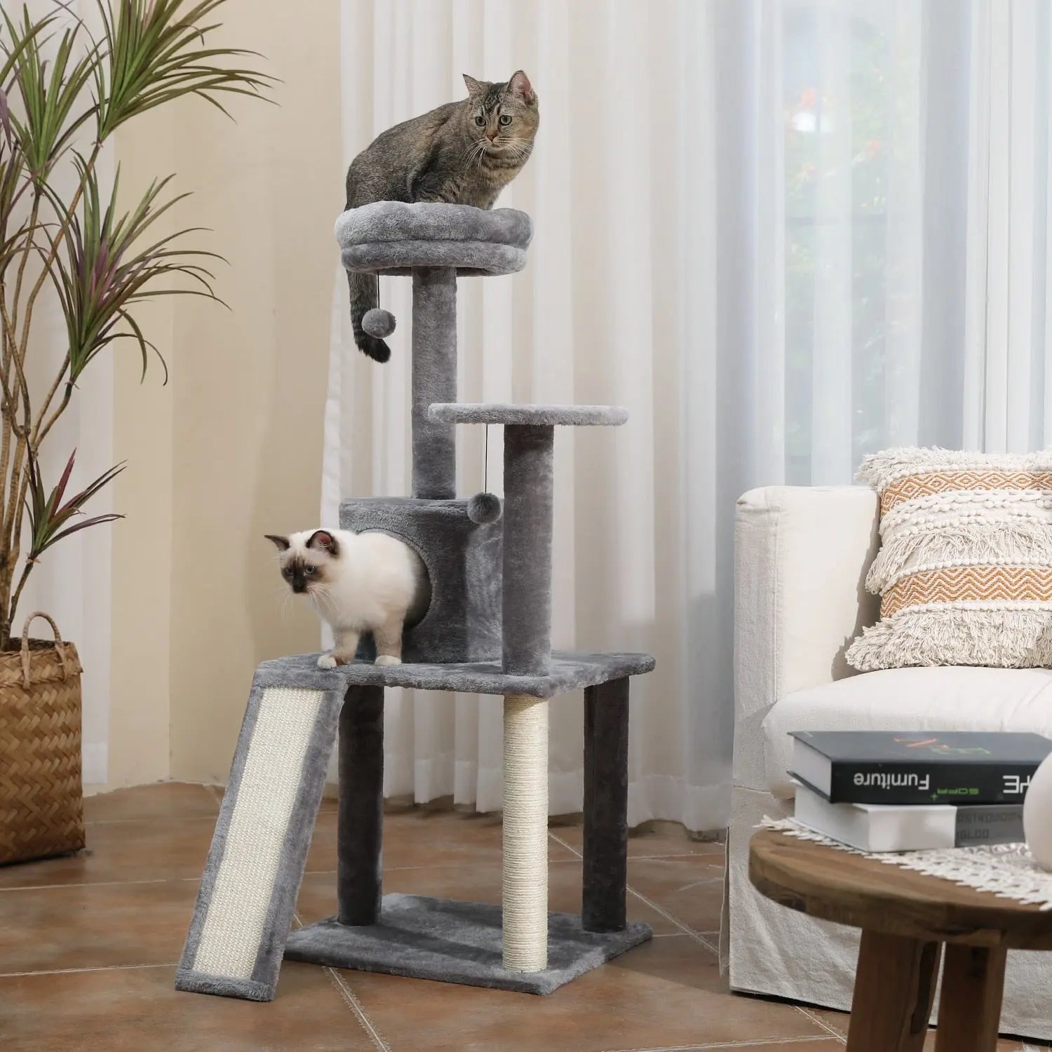 arbre à chat et griffoirs gris avec deux chat à côté canapé blanc