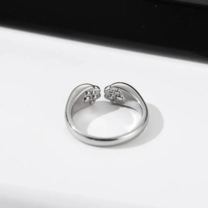 Bague Chat Ouverte et Réglable pour Femme posée sur une table blanche avec un fond noir au dessus