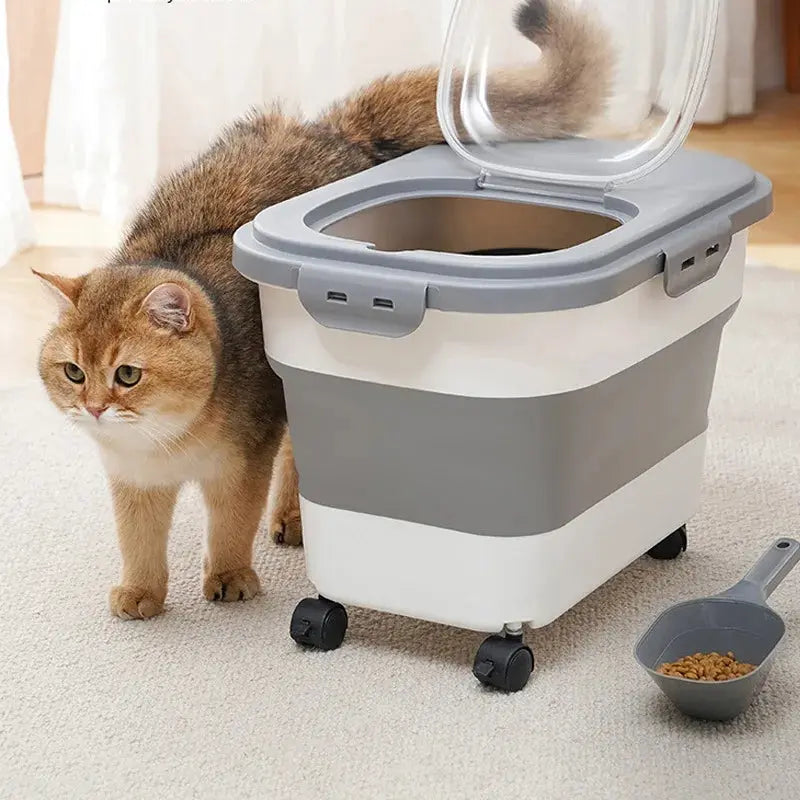 Boite à Croquette Pliable sur Roulettes avec Ouverture Rabattable avec un chat marron et noir et une pelle pour doser à droite sur un tapis blanc