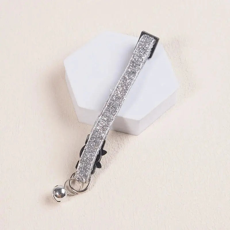 Collier Chat Anti Étranglement Élastique et Pailleté avec Clochette posé sur une forme blanche sur fond beige