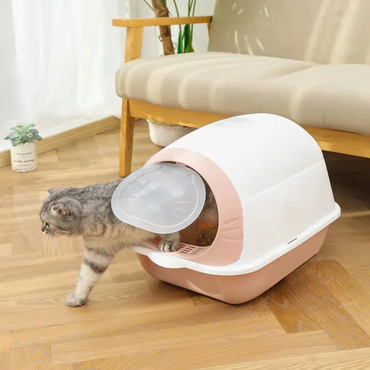 Litière Chaton Entièrement Fermée avec Porte Battante avec un chat en train de sortir et un canapé en bois derrière 