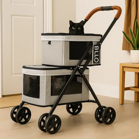 Poussette pour chat à deux étages avec sacs de rangement, pratique et confortable pour les promenades en extérieur, dans l'entrée d'une maison avec deux chats noir et un chat gris. Meuble en bois et plante verte dans pot blanc à droite.