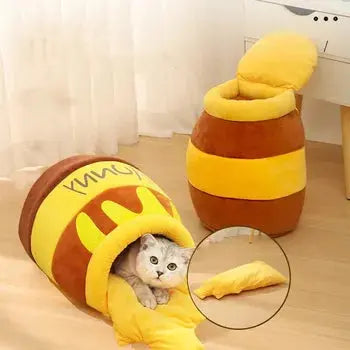 niche chat coussin lit  jolivase une niche au sol avec un chat dedans, une autre niche debout contre un meuble blanc à quatre pieds en bois
