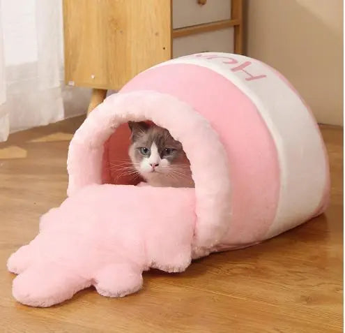 niche chat coussin lit  jolivase rose, une niche au sol avec un chat dedans, sur sol en bois et meuble derrière